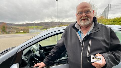 Taxifahrer steht vor seinem Auto.