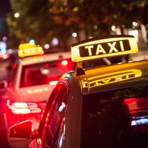 Ein Taxi mit rotem Rücklicht steht auf einer dunklen Straße
