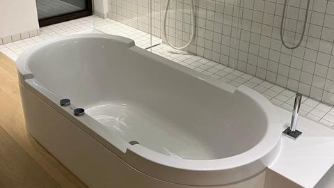 Eine weiße Badewanne vor einer begehbaren Dusche