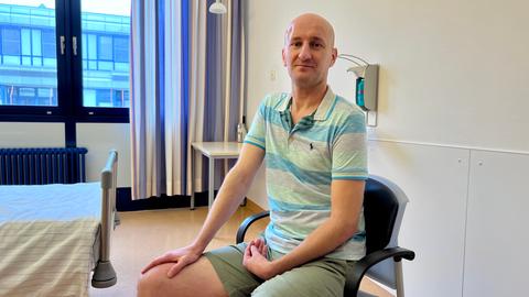 Mann mit Verband am Bein im Stuhl sitzend, Krankenhauszimmer