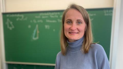 Lehrerin Maria Balakieva steht vor einer Tafel im Klassenraum. 