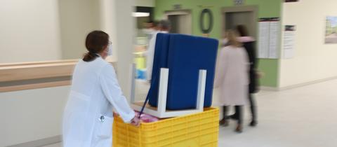 Eine Frau schiebt einen Container mit Möbelstücken durch den Neubau des Klinikums Höchst.