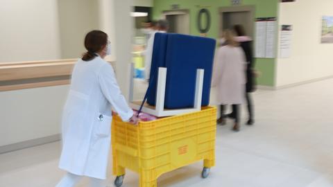 Eine Frau schiebt einen Container mit Möbelstücken durch den Neubau des Klinikums Höchst.