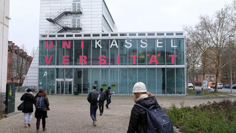 Studenten laufen auf ein Gebäude der Universität Kassel zu