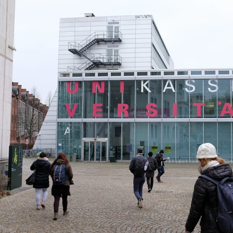 Studenten laufen auf ein Gebäude der Universität Kassel zu