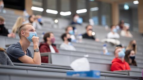 Studenten und Studentinnen sitzen in großem Abstand zueinander in einem Hörsaal.