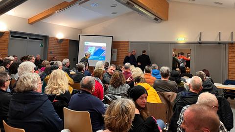Menschen sitzen bei einer Bürgerversammlung in Sinntal in einem Saal