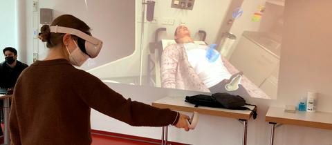 Frau mit VR Brille vor Leinwand mit Patientin