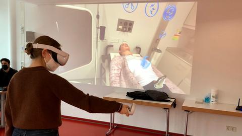 Frau mit VR Brille vor Leinwand mit Patientin