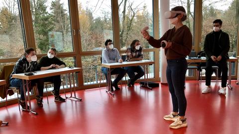 Frau mit VR Brille vor Leinwand mit Patientin