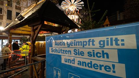 Am Eingang eines Weihnachtsmarktes hängt ein Banner mit der Aufschrift "Auch geimpft gilt: Schützen Sie sich und andere!"