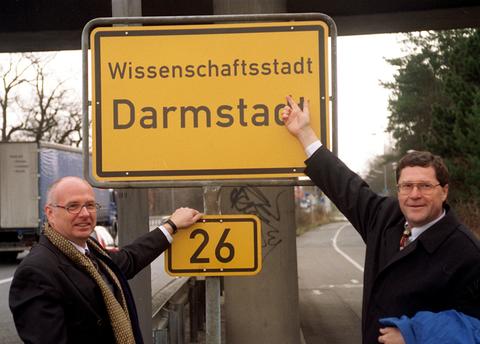 Der hessische Innenminister Gerhard Bökel (li.) und Darmstadts Oberbürgermeister Peter Benz enthüllen am 4.3.1998 das neue Ortsschild "Wissenschaftsstadt Darmstadt"