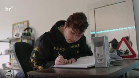 Der 14 Jahre alte Dylan sitzt in seinem Zimmer in einer Wohngruppe an einem Tisch und zeichnet