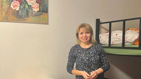 Frau in Zimmer mit Tisch und Hochbett, Bild mit Rosen an der Wand