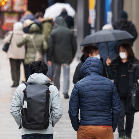 Passanten gehen bei Regenwetter über die Zeil in Frankfurt am Main. 