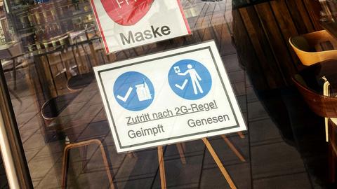 An der Ladentür eines Cafés hängt ein Schild, auf dem "Zutritt nach 2 G-Regel - geimpft, genesen, Maske" geschrieben steht.