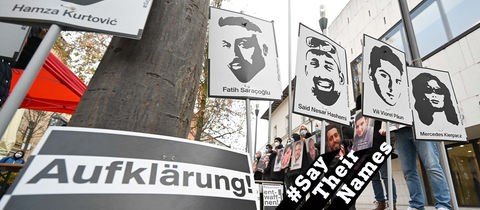 Mahnwache vor dem Landtag. Menschen halten Schilder mit den Portraits der Opfer hoch. Im Vordergrund ein Plakat mit der Aufschrift "Aufklärung".