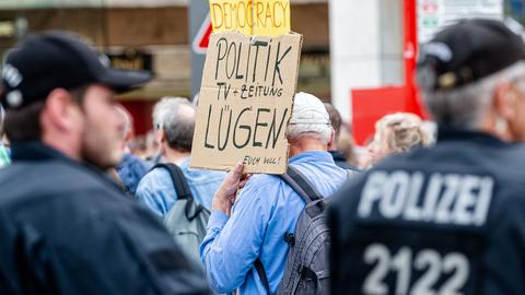 Demonstrant mit Lügenpresse Plakat inmitten Demo mit Polizei