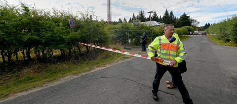 Ein Polizist sichert den Unglücksort, im Hintergrund ist der Sendemast zu erkennen.