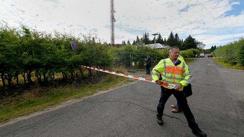 Ein Polizist sichert den Unglücksort, im Hintergrund ist der Sendemast zu erkennen.