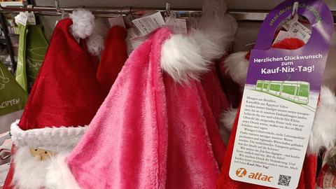 Info zum "Kauf-Nix-Tag" hängt an Weihnachtsmützen in einem Geschäft