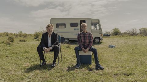 Zwei ältere Männer sitzen vor einem Campingmobil