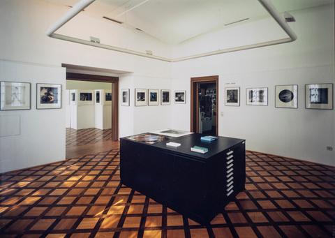 Ausstellungsraum mit Parkettboden, an den Wänden gerahmte Fotografien