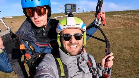 Zwei junge Männer fotografieren sich selbst beim Gleitschirmflug