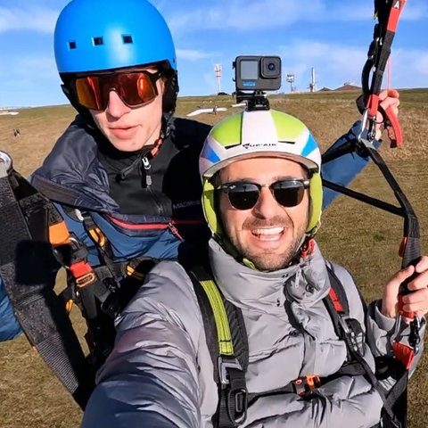 Zwei junge Männer fotografieren sich selbst beim Gleitschirmflug