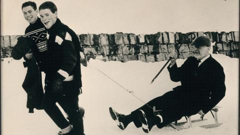 Zwei Jugendliche ziehen Rabbiner Isaak Emil Lichtigfeld auf einem Schlitten im Winter 1964/65.