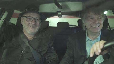 Zwei ältere Männer sitzen in einem Auto.