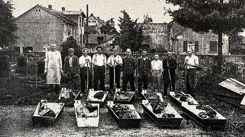 Historyczne zdjęcie S/W, ludzie stojący na ulicy za trumnami na świeżym powietrzu.