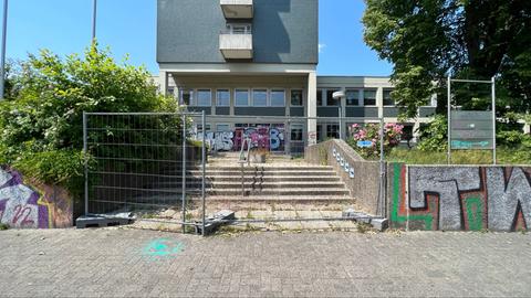 Auf dem Foto ist das alte Versorgungsamt in der Frankfurter Straße in Kassel zu sehen. Vor dem grauen Gebäude aus den 1970er Jahren haben die Architects 4 Future mit grellgrüner Farbe das #ichbinnochgut-Aktionssymbol gauf den Asphalt gesprüht.