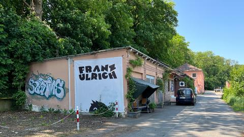 Auf dem Foto ist das Franz Ulrich in Kassel zu sehen. Der Name ist mit schwarzer Schrift auf den weißen Untergrund des Gebäudes gemalt.