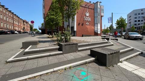 Auf dem Foto ist die Kaufburg in der Friedrich Ebert Straße in Kassel zu sehen. Vor dem rot verklinkerten Gebäude haben die Architects 4 Future mit grellgrüner Farbe das #ichbinnochgut-Aktionssymbol auf den Asphalt gesprüht.