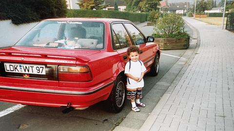 Fikri Anıl Altıntaş als kleiner Junge vor dem Familienauto