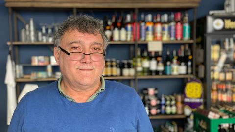 Nazim Alemdar, Betreiber des "Yok Yok", steht in seinem Laden. Er trägt einen blauen Pulli und eine Brille. Im Hintergrund sind Getränkeflaschen und Chipstüten zu sehen.