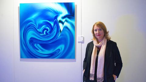 Die Künstlerin Cornè Theron steht neben einem Bild ihrer "Essence"-Serie. 