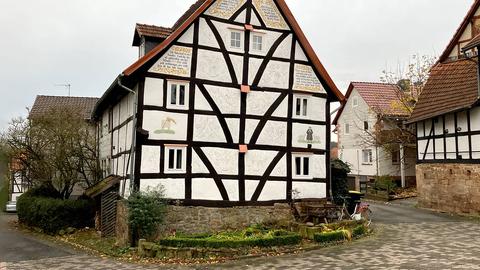 Außenansicht eines kleinen Fachwerkhauses, eingebunden in eine dörfliche Straße.