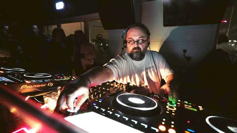 DJ Ata Macias während des Auflegens an den Plattenspielern in einem Club.