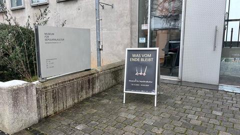 Vor der Tür des Museums für Sepulkralkultur in Kassel steht ein Aufsteller mit Hinweis auf die Ausstellung. 