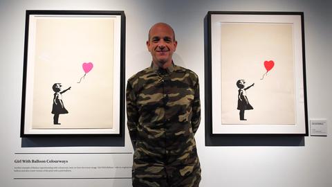 Fotograf Steve Lazarides, Banksys ehemaliger Manager, steht zwischen Werken des britischen Straßenkünstlers Banksy während einer Medienvorschau in Australien 2019.