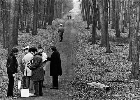 Schwarz-weiß-Fotografie: Gruppe von Männern im Wald im Gespräch, am rechten Bildrand liegt eine Leiche