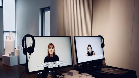 Zwei Monitore zeigen die Gesichter zweier Frauen.