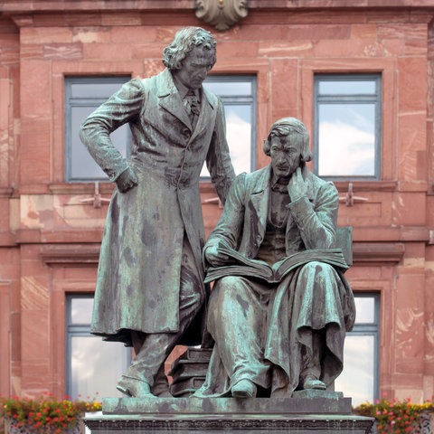 Das Brüder-Grimm-Denkmal von 1896 mit Wilhelm Grimm sitzend und Jacob Grimm stehend, aufgenommen am 02.09.2015 vor dem historischen Rathaus auf dem Marktplatz in Hanau 