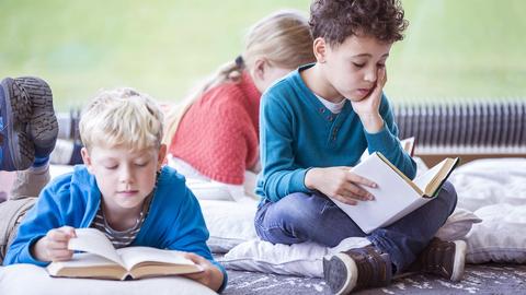 Kinder sitzen auf einem Teppich und lesen