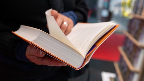 Eine Person schlägt ein Buch auf der Frankfurter Buchmesse auf.
