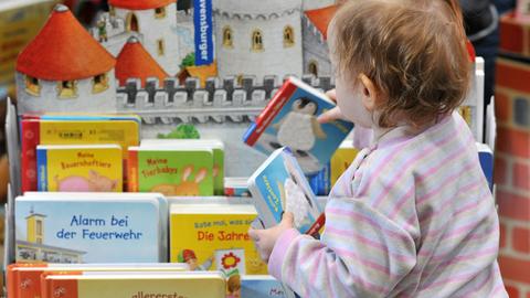 Kind räumt Bücher in einen Bücherständer