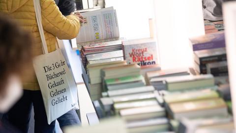 Eine Frau blättert während des ersten Besuchertags der Buchmesse 2021 an einem Stand in einem Buch. 