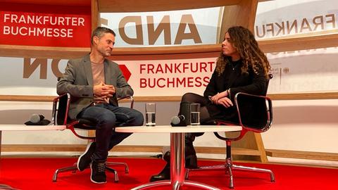 Meron Mendel sitzt mit Alena Jabarine auf der Bühne im Pavillion auf der Agora